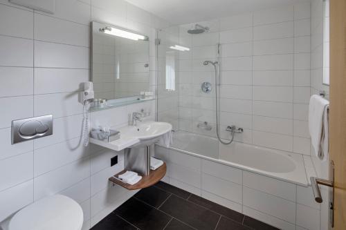 W łazience znajduje się umywalka, prysznic i wanna. w obiekcie Hotel Phoenix w mieście Zermatt