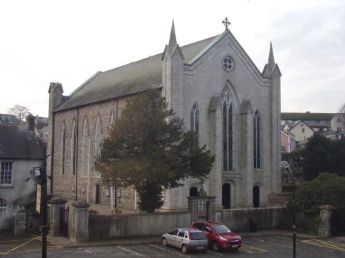 two cars parked in a parking lot in front of a church at Woodstock Arms in Inistioge