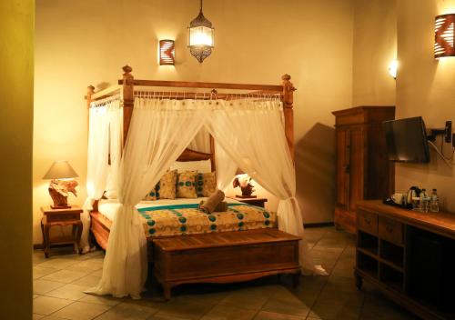 a bedroom with a canopy bed and a television at N'taba River Lodge & Spa in Port St Johns