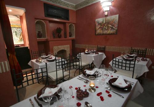 un comedor con mesas blancas y sillas con platos y vasos en Riad Alili en Marrakech