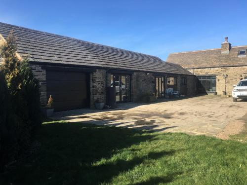 um edifício com garagem e um carro estacionado ao lado em The Coach House & The Stables Holiday Homes Windy Bank Hall Green Moor Yorkshire Peak District em Wortley