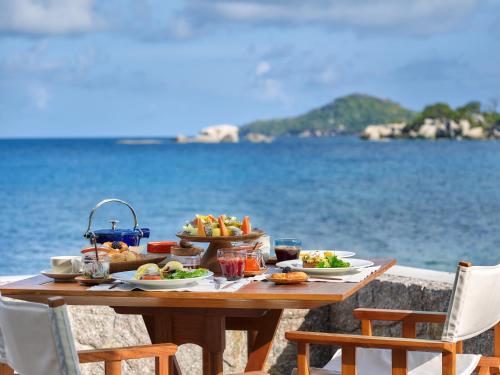 
a table topped with plates of food on top of a beach at Six Senses Zil Pasyon in Felicité
