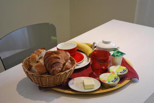 a breakfast tray with a basket of bread and butter at Logis Hôtel & Restaurant Les Perce-Neige in Bonnétage