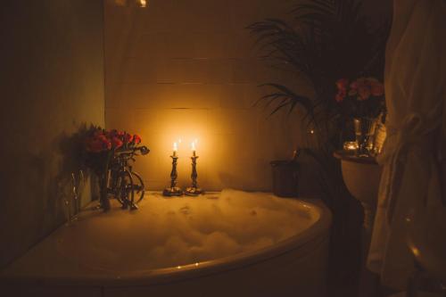 La salle de bains est pourvue d'une baignoire avec 2 bougies et des fleurs. dans l'établissement Villa Sjötorp, à Ljungskile