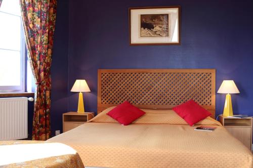 オーディエルヌにあるchambres d'hotes du Manoir de Suguensouのベッドルーム1室(大型ベッド1台、赤い枕2つ付)