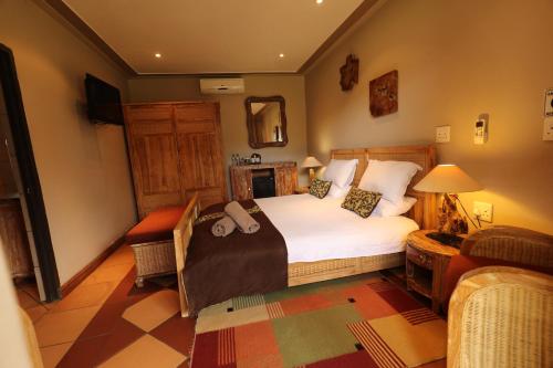 a bedroom with a bed and a chair and a mirror at N'taba River Lodge & Spa in Port St Johns