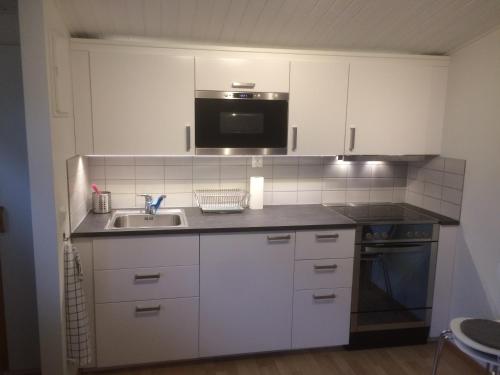 eine Küche mit einer Spüle und einer Mikrowelle in der Unterkunft Lillstugan Falköpingsvägen in Broddetorp