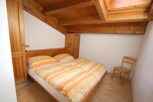 Ce lit se trouve dans un dortoir doté d'un plafond en bois. dans l'établissement Résidence Mont-Calme, à Nendaz