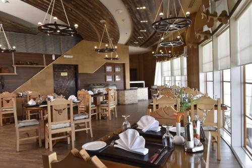 a dining room with tables and chairs and windows at Awaliv Hotel in Taif