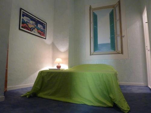 a bedroom with a green bed with a mirror at Au Coeur du vieux Nice in Nice