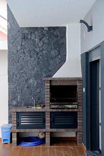 a kitchen with a stone wall with a fireplace at Sunset Holiday Home in Fernao Ferro