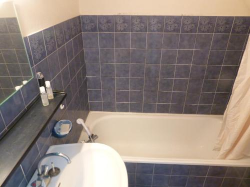 La salle de bains est pourvue de carrelage bleu, d'une baignoire et de toilettes. dans l'établissement Le Frioul, au Grau-du-Roi