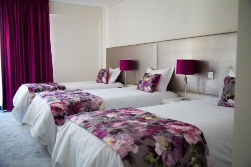 two beds in a hotel room with purple curtains at Tomas Guest House II in Covilhã