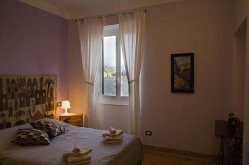 een slaapkamer met een bed en een raam met handdoeken erop bij Piume Verdi in Genua