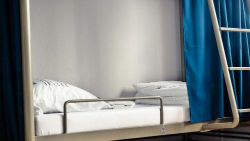 a bunk bed in a room with a blue curtain at ODA Hostel in Prishtin&euml;