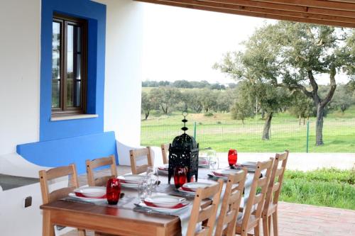 a dining room table with chairs and a large window at Monte Azul - Casas de Campo do Junqueirinho in Bicos