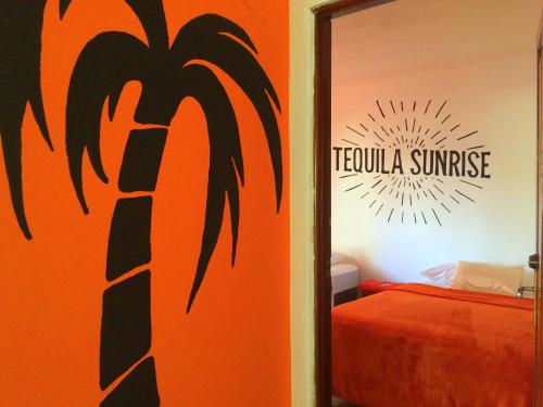 a bedroom with an orange wall with a palm tree mural at Tequila Sunrise Hostel in Guatemala