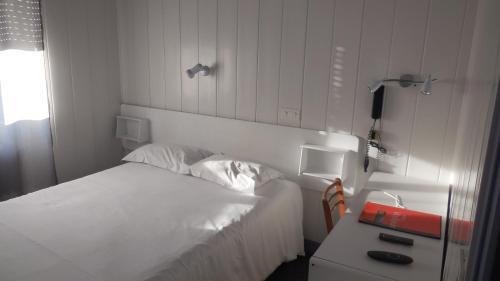 a bedroom with a white bed and a desk with a phone at Logis des Voyageurs in Pont-de-Salars