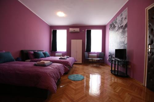 a purple room with two beds and a couch at Hostel Fine in Belgrade