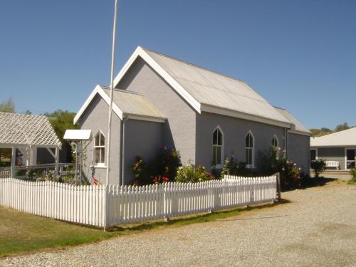 a church with a white fence in front of it at St Andrews Church Nave in Ophir