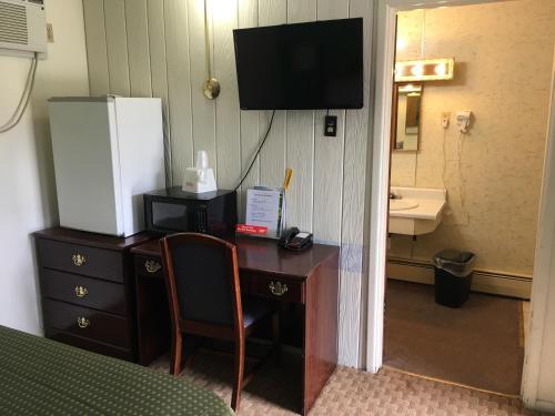 um quarto com uma secretária e uma televisão na parede em Travelers Inn Olney em Olney