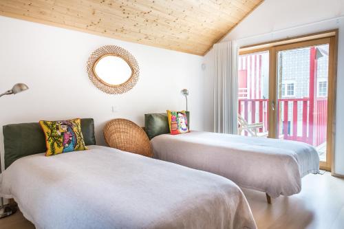 two beds in a room with a window at Cestaria Costa Nova in Costa Nova