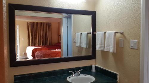 a bathroom mirror with a sink in a hotel room at American Regency Inn in Williams