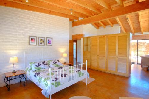 a bedroom with a white bed and a wooden ceiling at Rancho El Rossinyol in Valle de Guadalupe