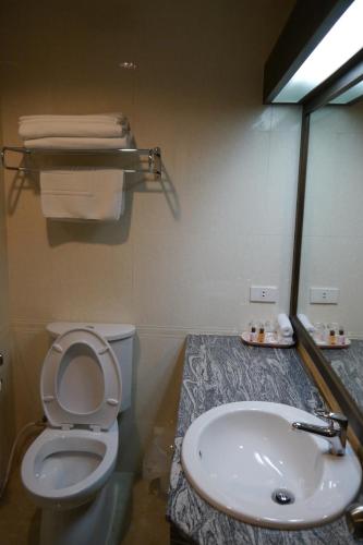 a bathroom with a sink and a toilet and a mirror at Lertnimit Hotel in Chaiyaphum
