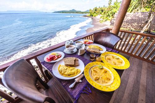 una mesa con desayuno en un balcón con vistas al océano en Seraya Shores Bali, en Seraya