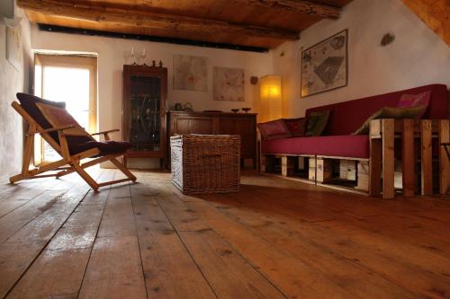 a living room with a red couch and a wooden floor at Casa Acquarossa in Rubiana