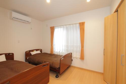 Un dormitorio con dos camas y una ventana. en Fujinokura Village, en Fujikawaguchiko