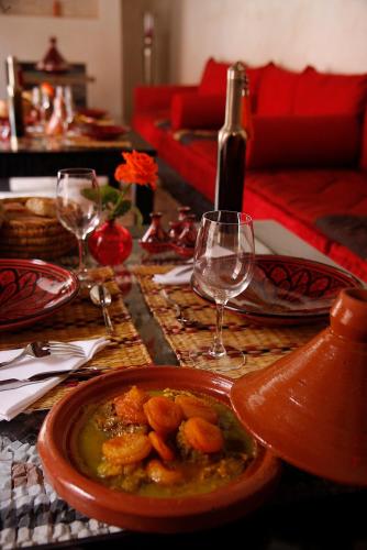 a table with a plate of food and wine glasses at Riad Alili in Marrakech