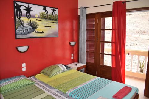 een slaapkamer met een bed met een rode muur bij Apartamento Fritzi in Ponta do Sol