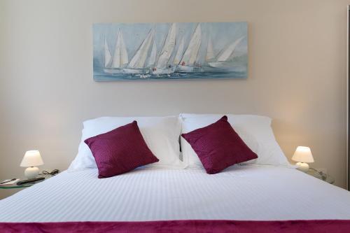 a white bed with two purple pillows in a bedroom at Central Boutique Apartments with balconies, in walking distance to the sea in Zadar