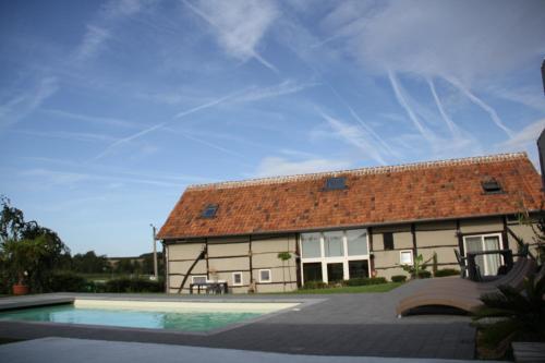 uma casa com uma piscina em frente em Rikkeshoeve vakantiewoning em Sint-Truiden