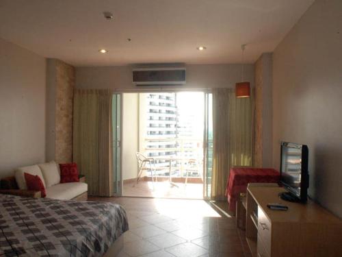 Pokój hotelowy z łóżkiem, telewizorem i balkonem w obiekcie Apartments At View Talay w Pattaya South