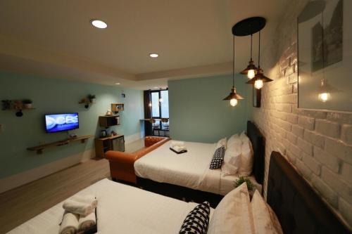 a room with two beds and a couch and a tv at Adagio Bangkok in Bangkok