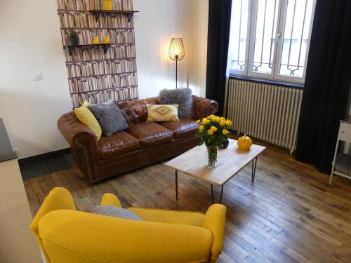 a living room with a couch and a table with flowers at Entre Nous - La Poste in Saumur