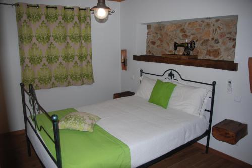 a bedroom with a bed with white sheets and green pillows at Casas no Terreiro in Penacova