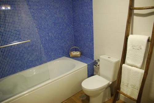 a bathroom with a toilet and a blue tiled wall at Casas no Terreiro in Penacova