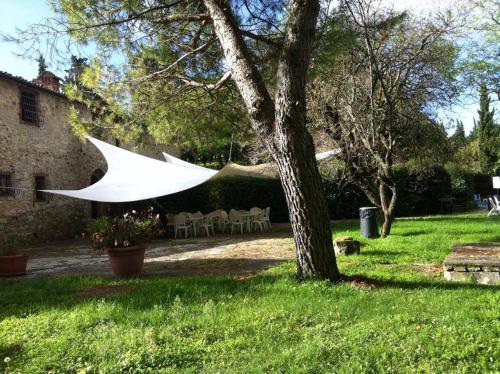 a white umbrella hanging from a tree in a yard at Albergo Il Colombaio in Castellina in Chianti