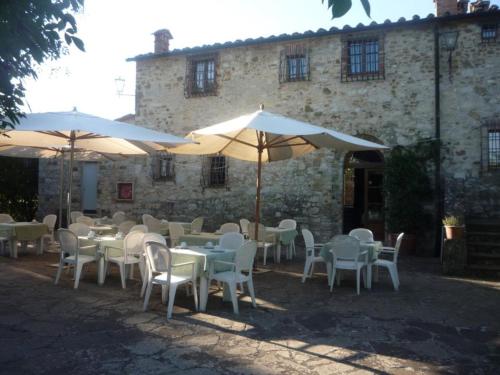 a group of tables and chairs with umbrellas in front of a building at Albergo Il Colombaio in Castellina in Chianti