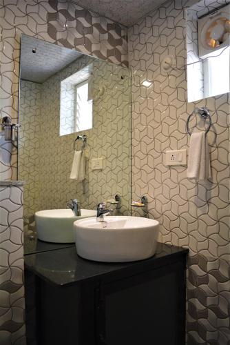 Un baño con lavabo y un espejo grande. en Hotel BluRay, en Belgaum