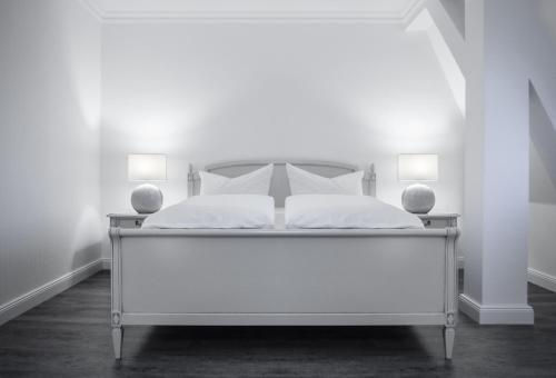 Cama blanca en habitación blanca con 2 lámparas en Spreezeit Hotel, en Lübbenau
