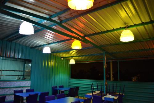 a dining room with tables and chairs and lights at Hotel BluRay in Belgaum