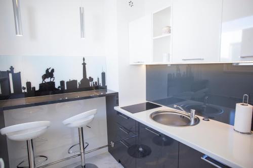 a kitchen with a sink and a counter with stools at Dia Belgrade Arena Apartment in Belgrade