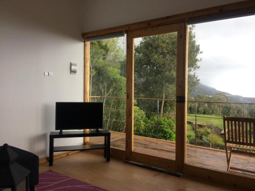 a living room with a television and a sliding glass door at Intact Farm Resort in Velas
