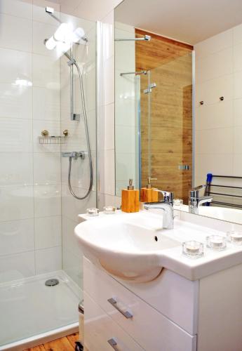 a white bathroom with a sink and a shower at ApartamentyPrzyMorzu Solna 201 - W centrum blisko morza in Kołobrzeg