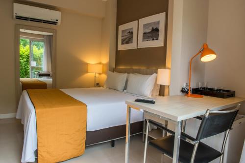a hotel room with a bed and a desk and a bed and a desk at Link Stay Flats in Rio de Janeiro